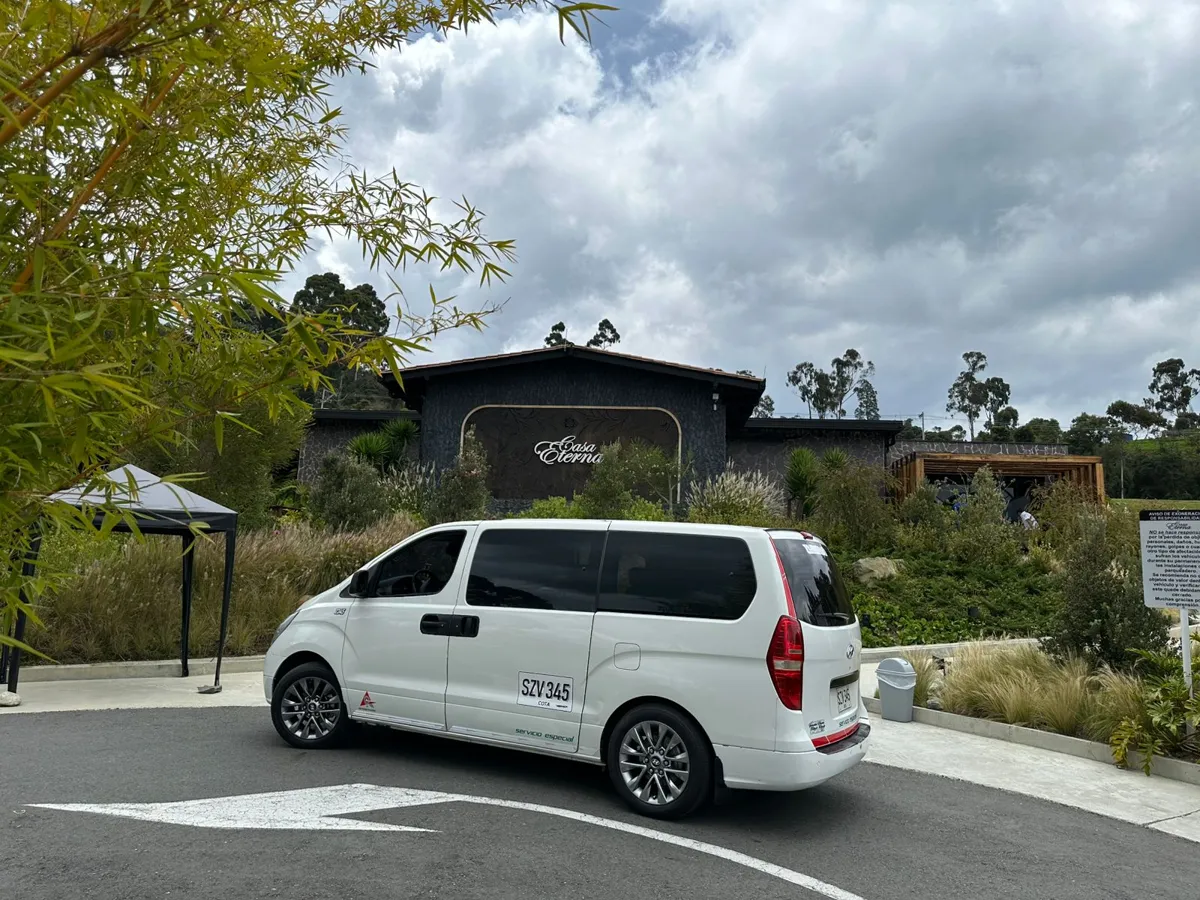 Van blanca de 8 pasajeros de Medellín Tours estacionada en Casa Eterna
