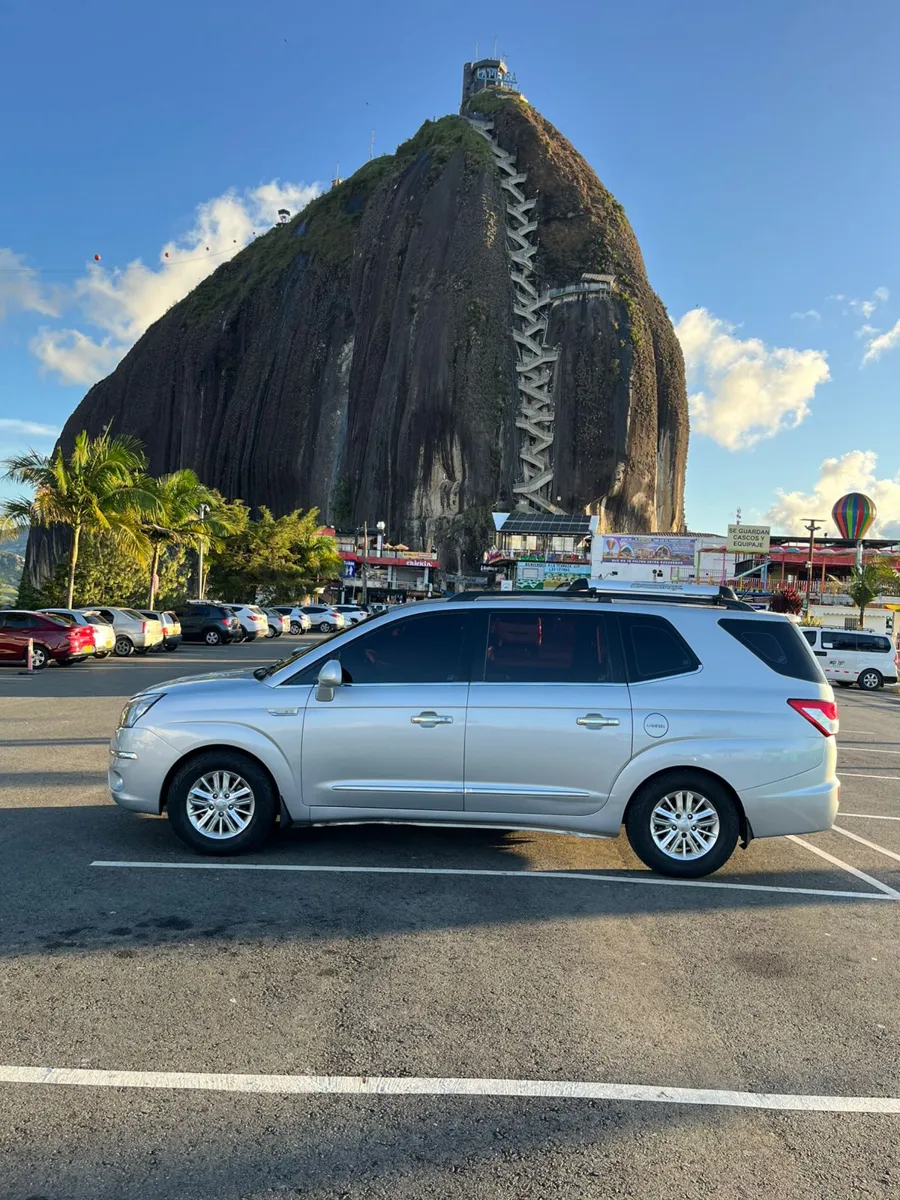 Van plateada de 8 pasajeros de Medellín Tours frente a la Piedra del Peñol en Guatapé
